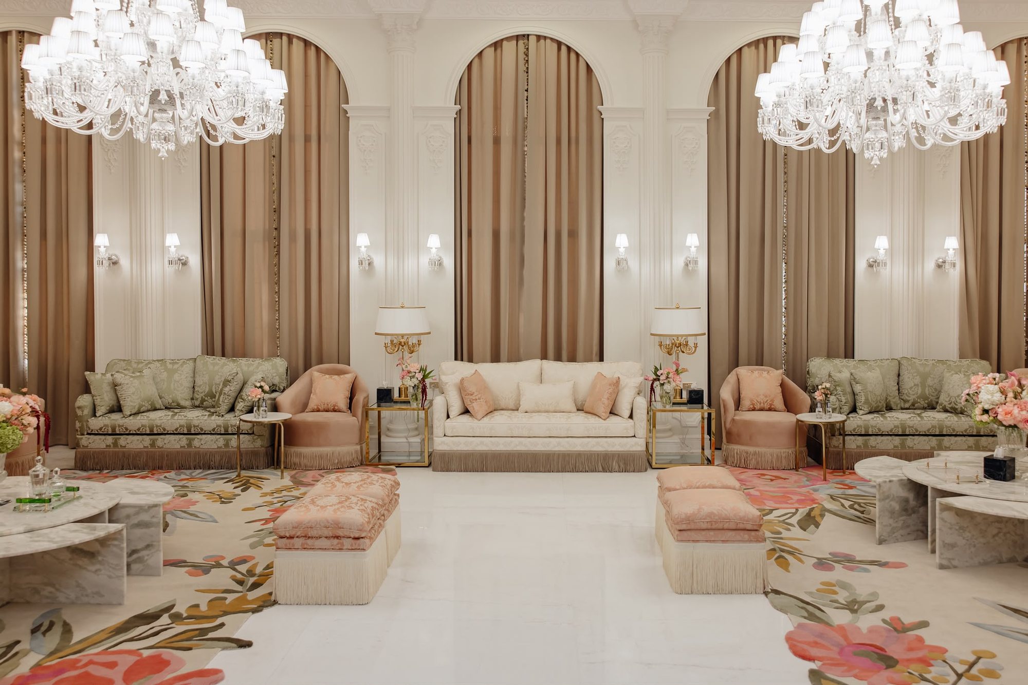 Symmetrical real project seating with arched wall panels, chandeliers, sage chairs, cream sofa, and blush ottomans